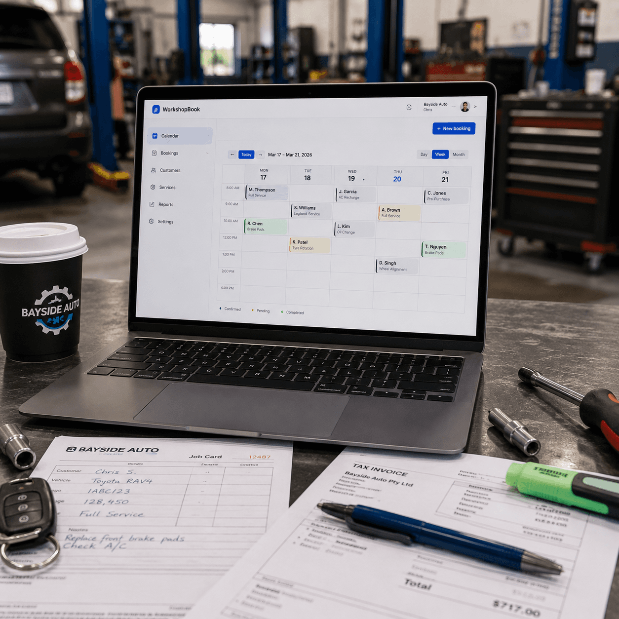 WorkshopBook booking calendar open on a laptop at an automotive workshop bench